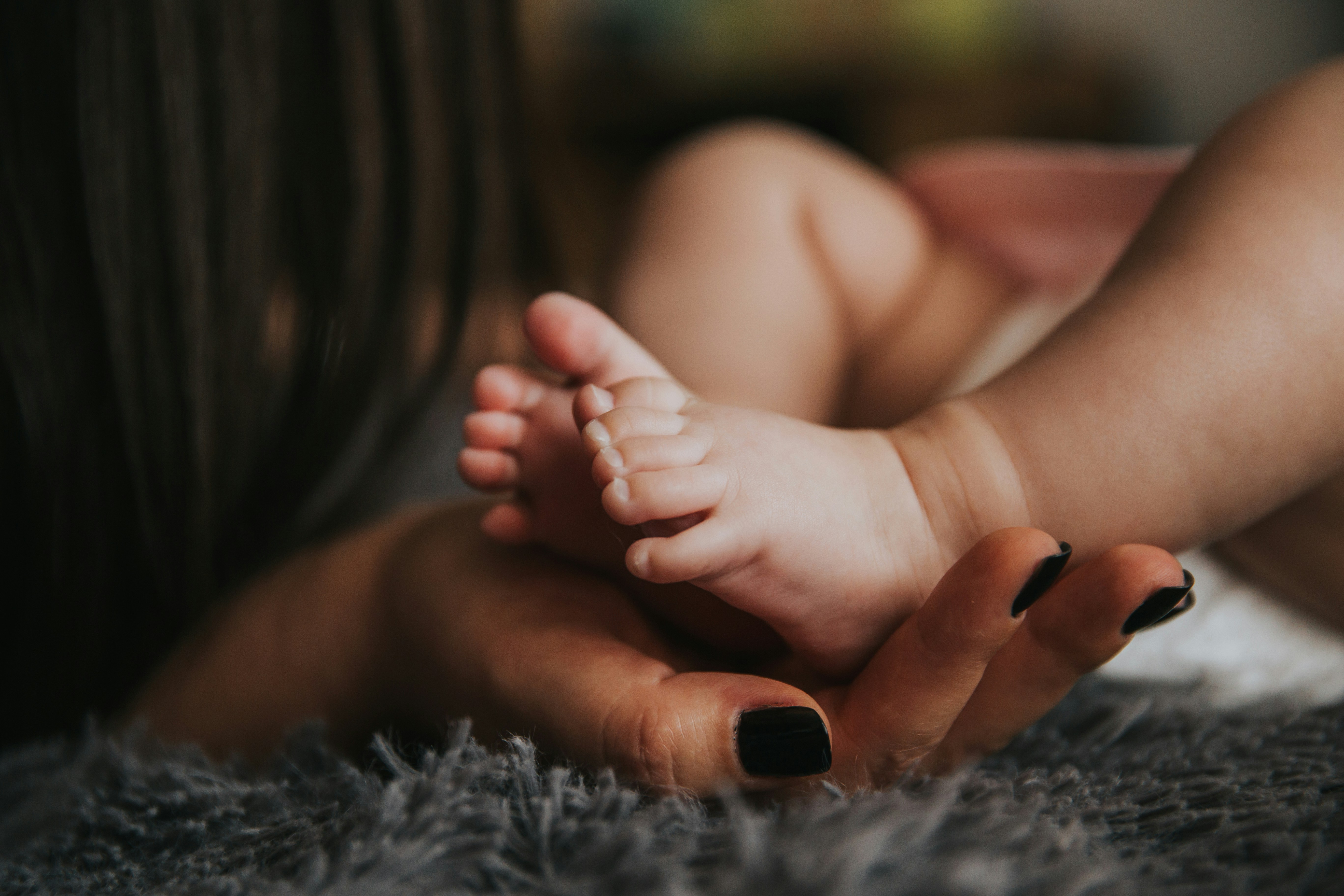 A hand holding the feet of a newborn